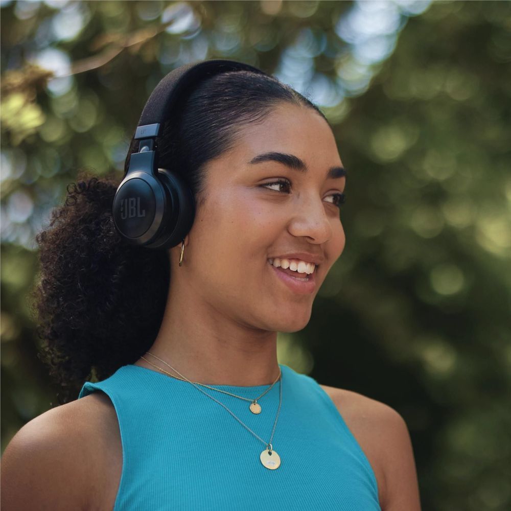 Woman wearing black JBL wireless on-ear headphones, smiling side profile