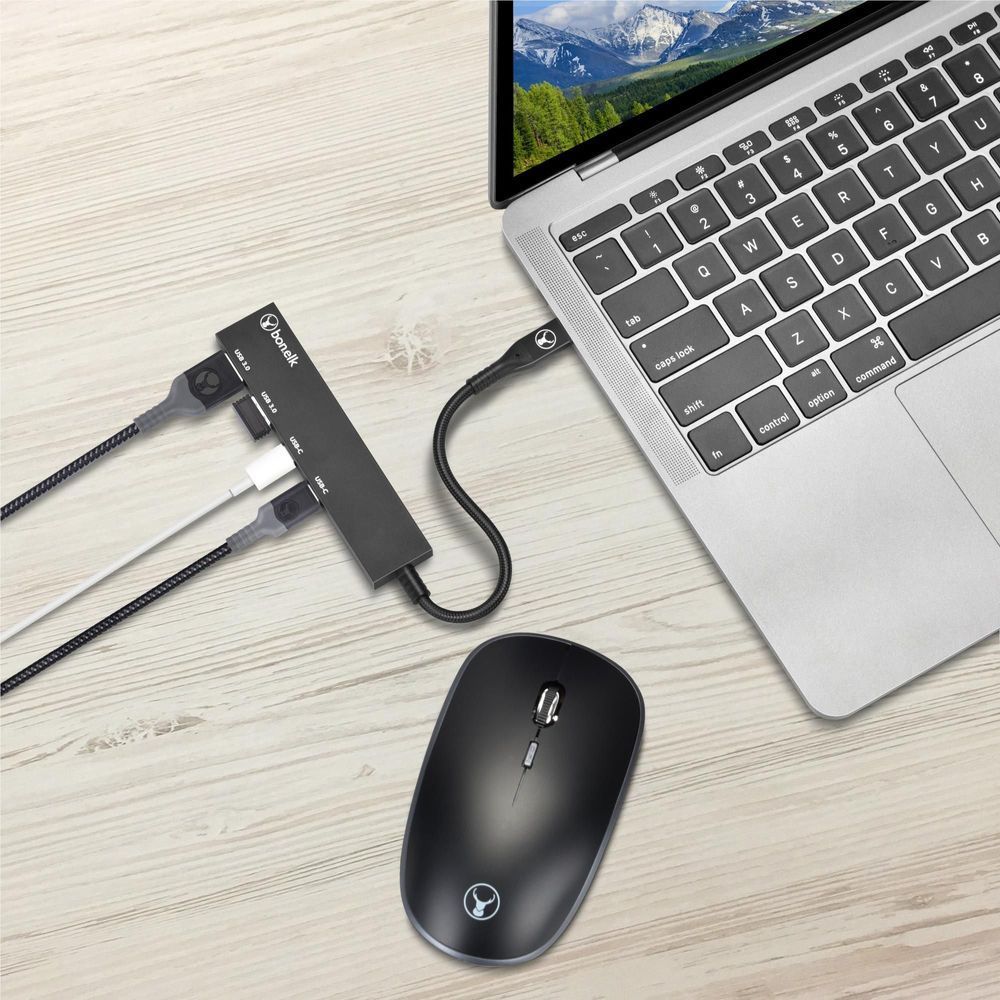 Black USB-C hub connected to laptop with mouse nearby