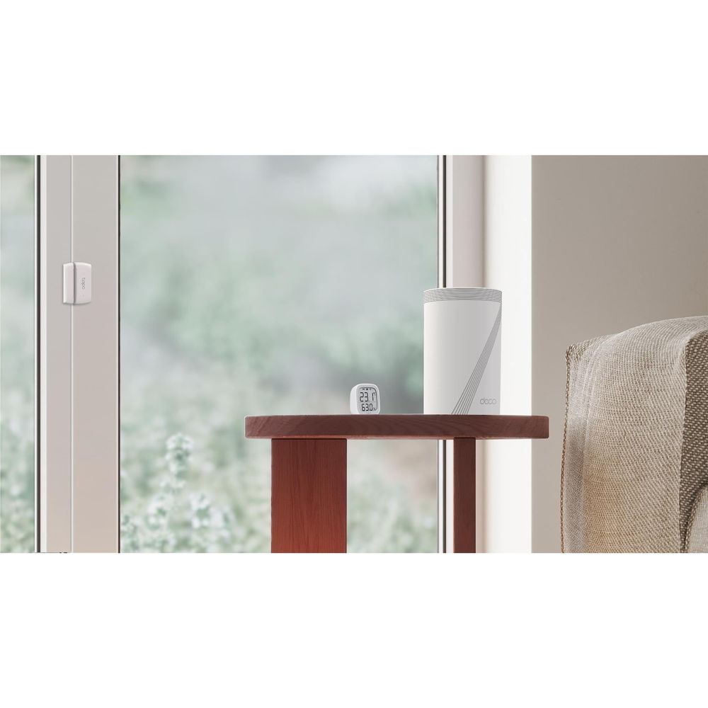 TP-Link Deco mesh Wi‑Fi node, white cylindrical unit on a table near a window