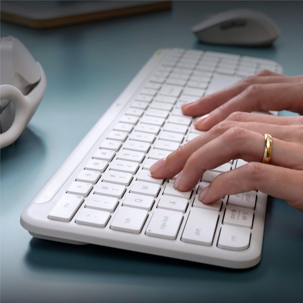 Off-white wireless keyboard being typed on, with hand resting on keys