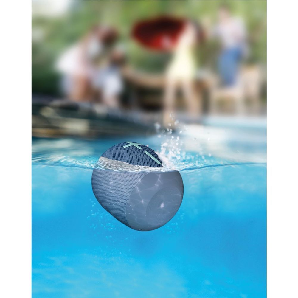 Cobalt blue portable Bluetooth speaker floating with droplets on the fabric grille