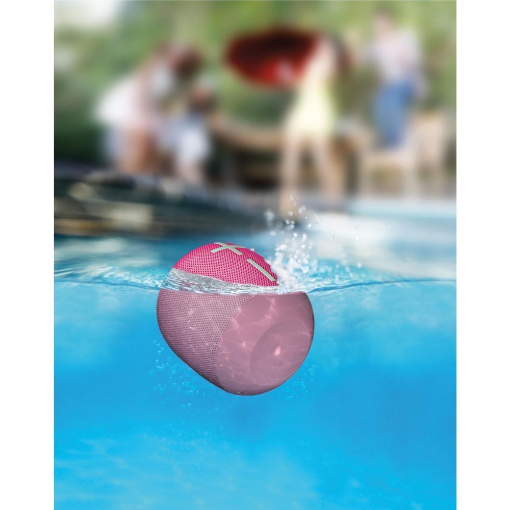 Hyper Pink portable Bluetooth speaker floating underwater, mesh top with plus icons