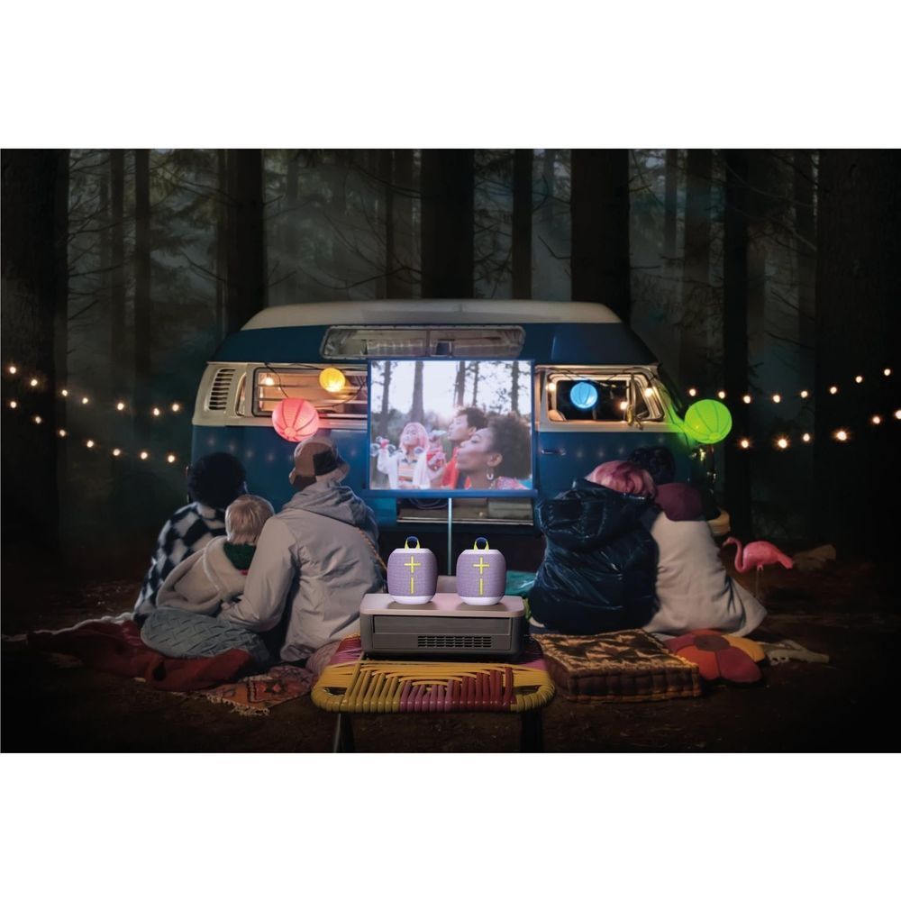 Multiple lilac portable Bluetooth speakers with lime accents on a camping table