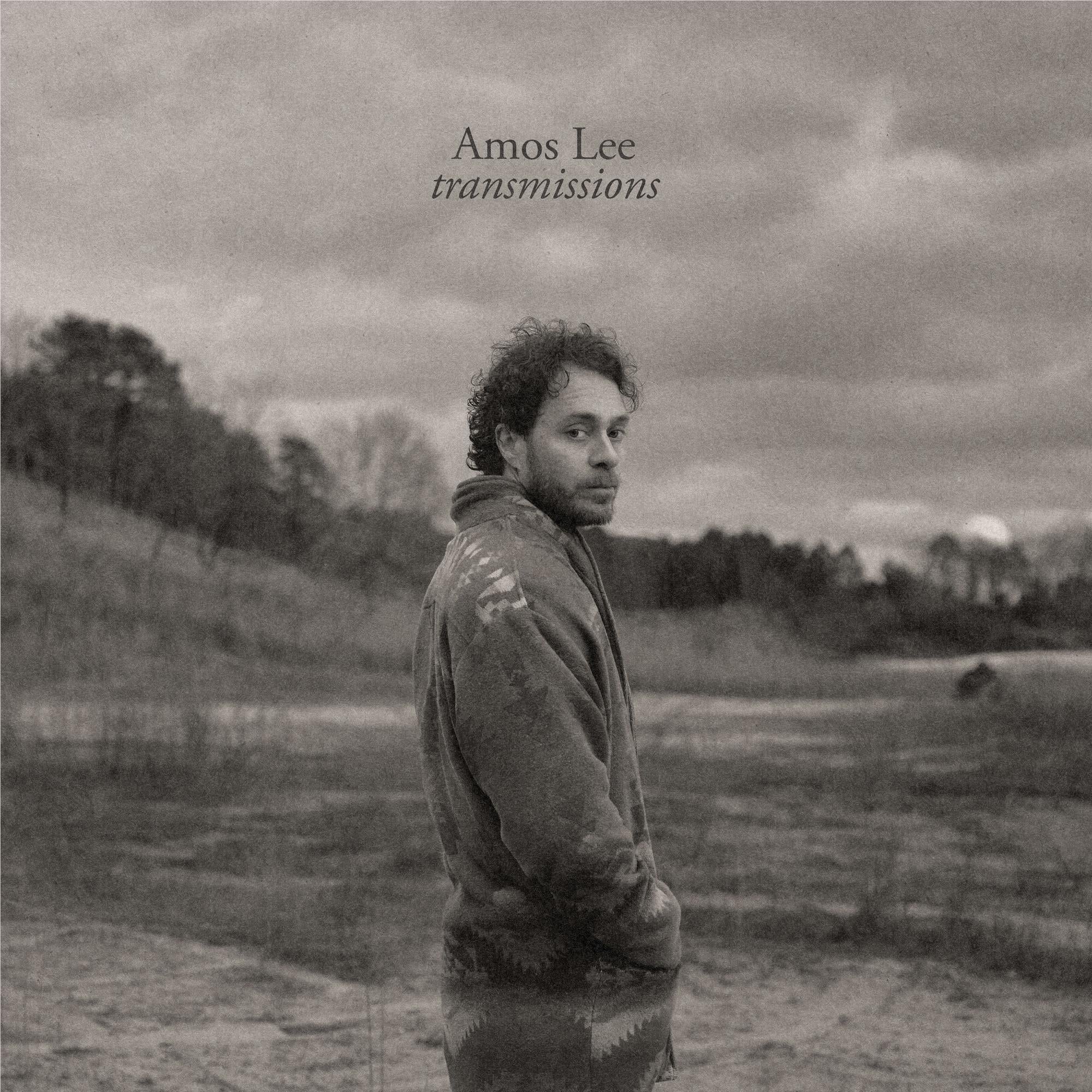 Grayscale album cover featuring Amos Lee outdoors, wearing a hooded jacket and standing
