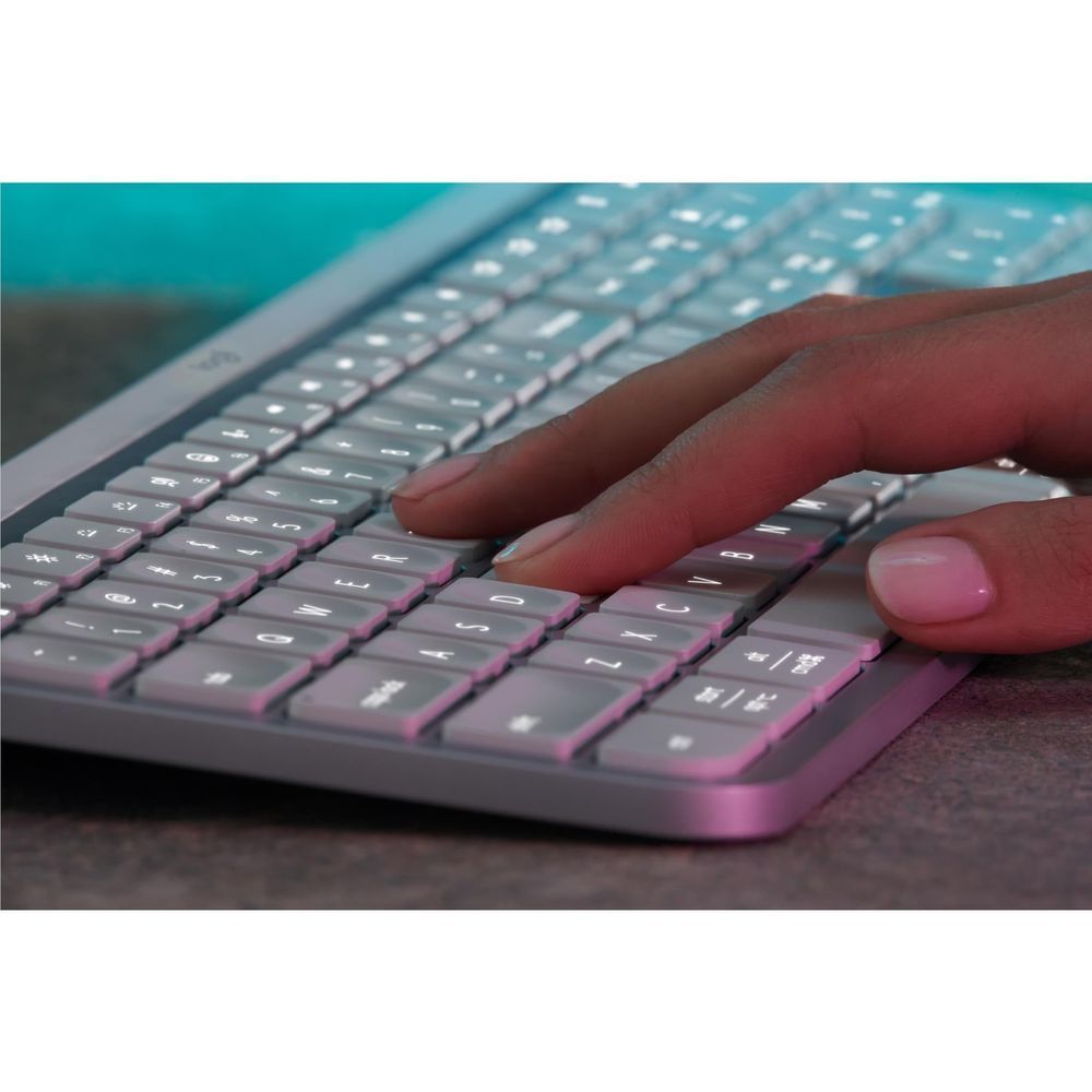 Pale grey keyboard with pink backlit keys, close-up of hand pressing keys