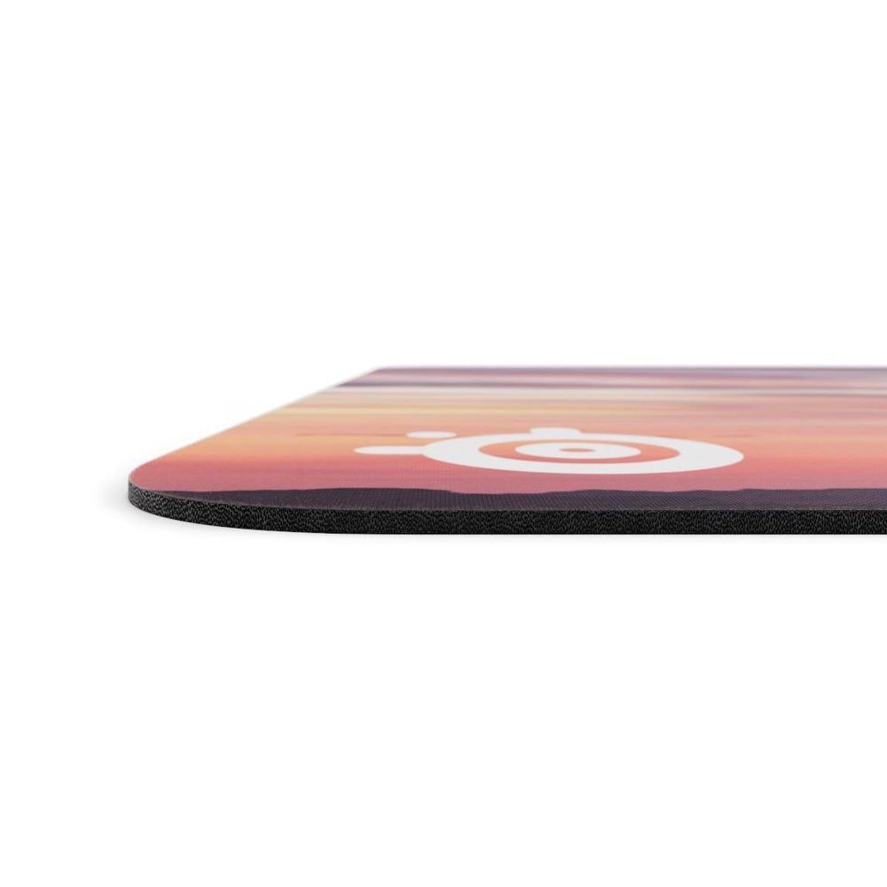 Gaming mouse pad edge close-up: purple-pink print over dark textured surface
