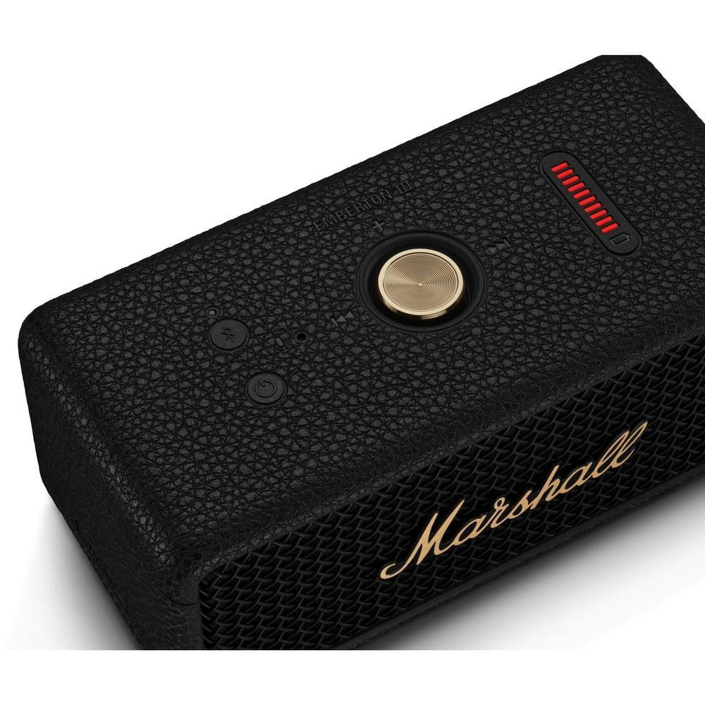Black portable Bluetooth speaker side closeup with gold knob, red control, and logo