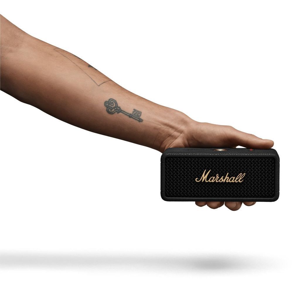 Black portable Bluetooth speaker in hand, showing gold 'Marshall' logo on grille