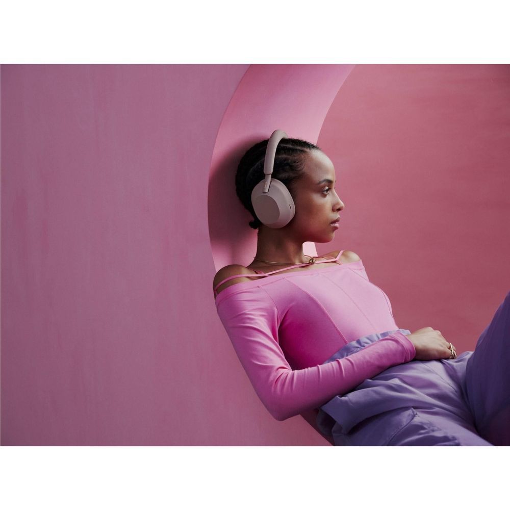 Smokey pink over-ear wireless headphones worn by a person in a pink long-sleeve top