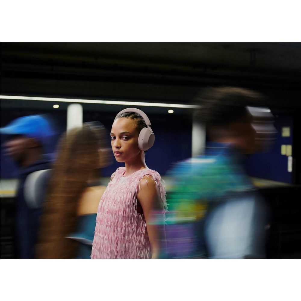 Smokey pink over-ear wireless headphones worn by a person wearing a light pink top