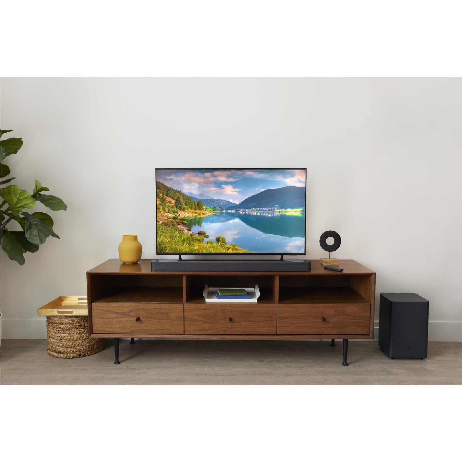 Black soundbar and wireless subwoofer on a TV console in a living room setup.