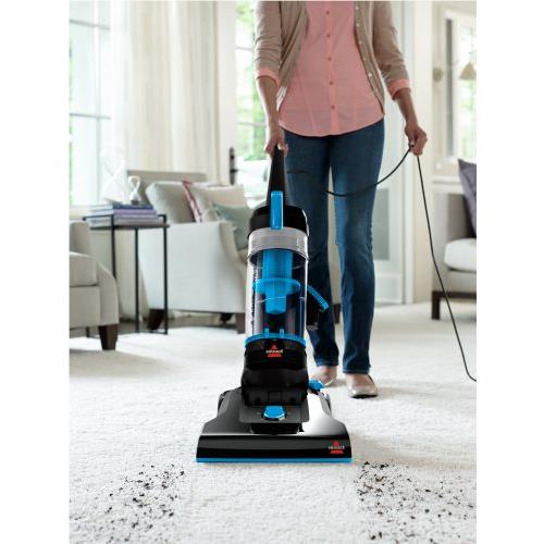 Bagless upright vacuum cleaner in use, cleaning carpet with powered floor nozzle