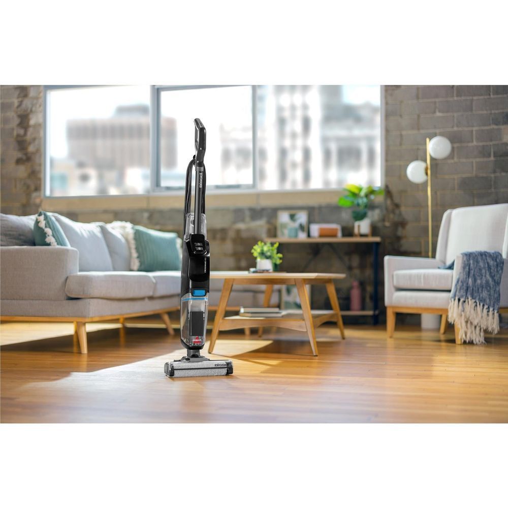 Upright wet and vacuum hard floor cleaner on hard flooring, black with blue tank.