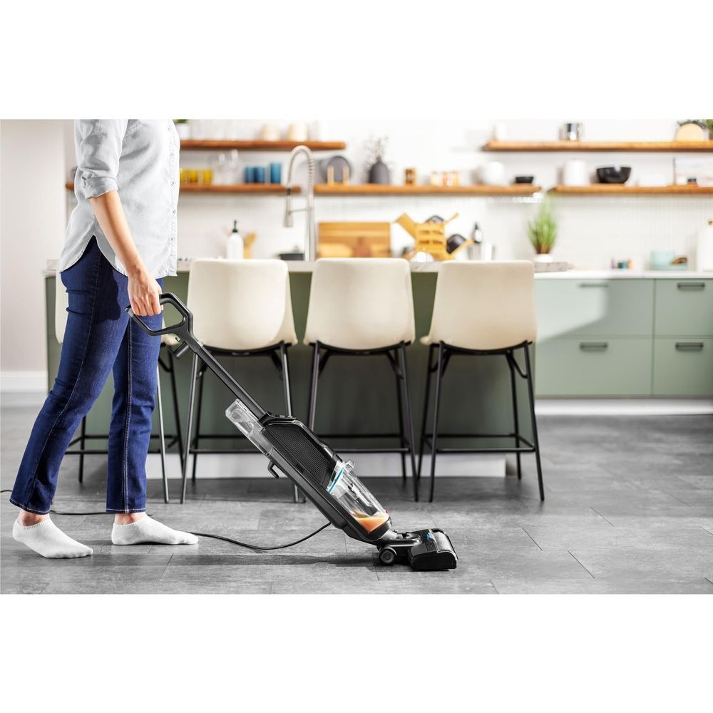 Upright wet and vacuum hard floor cleaner in use on tile, black with blue tank.