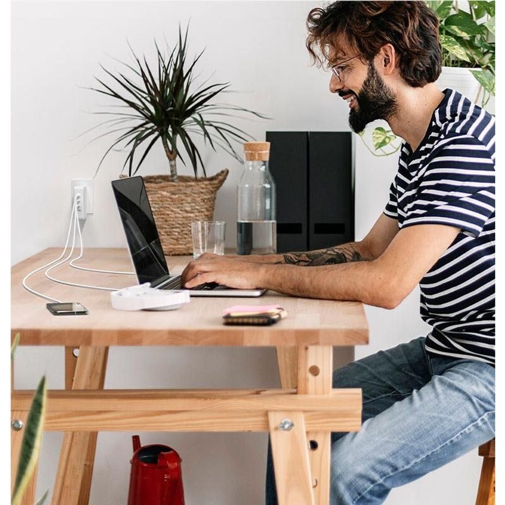 White power charger and cables on desk beside a laptop