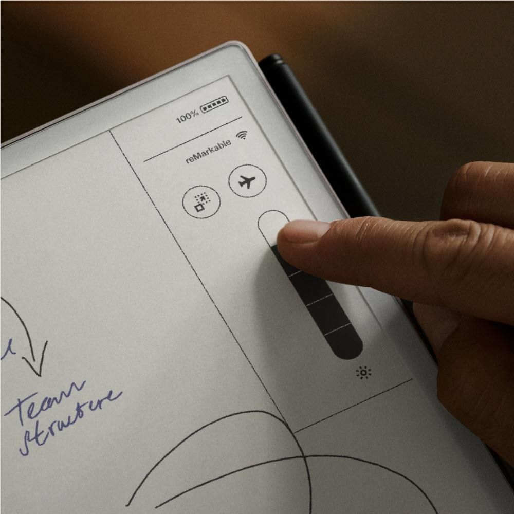 Hand touching tablet screen with UI icons and diagrams on white page