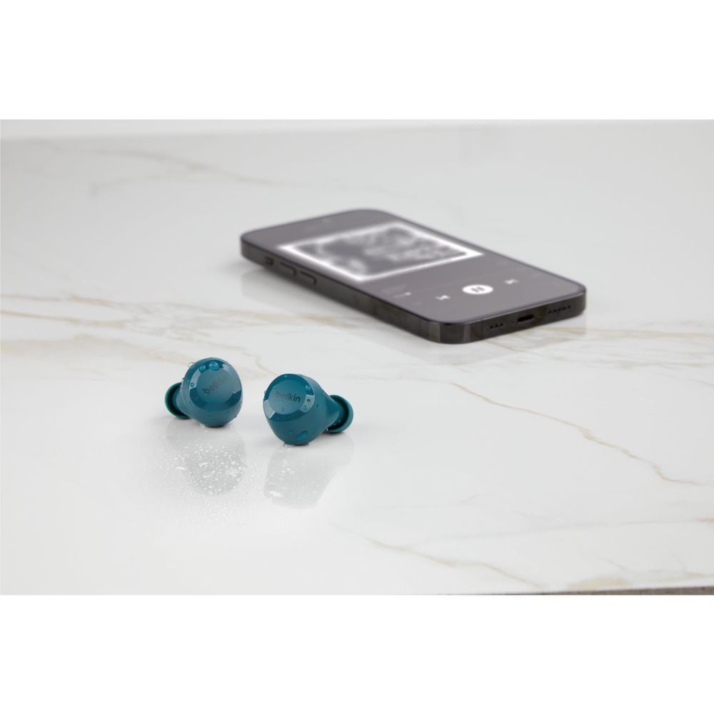Teal wireless earbuds on a light surface with a smartphone nearby