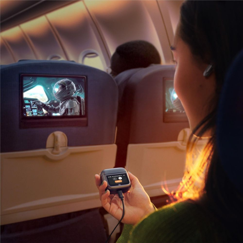 Person holding a black JBL earbud charging case with earbuds app screen visible