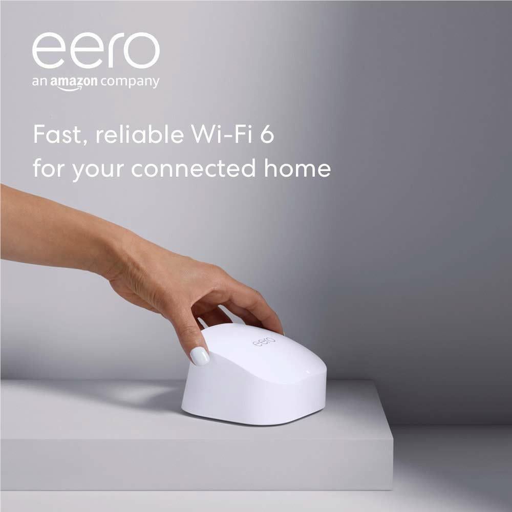 White eero mesh Wi-Fi router placed on a table with a hand adjusting it