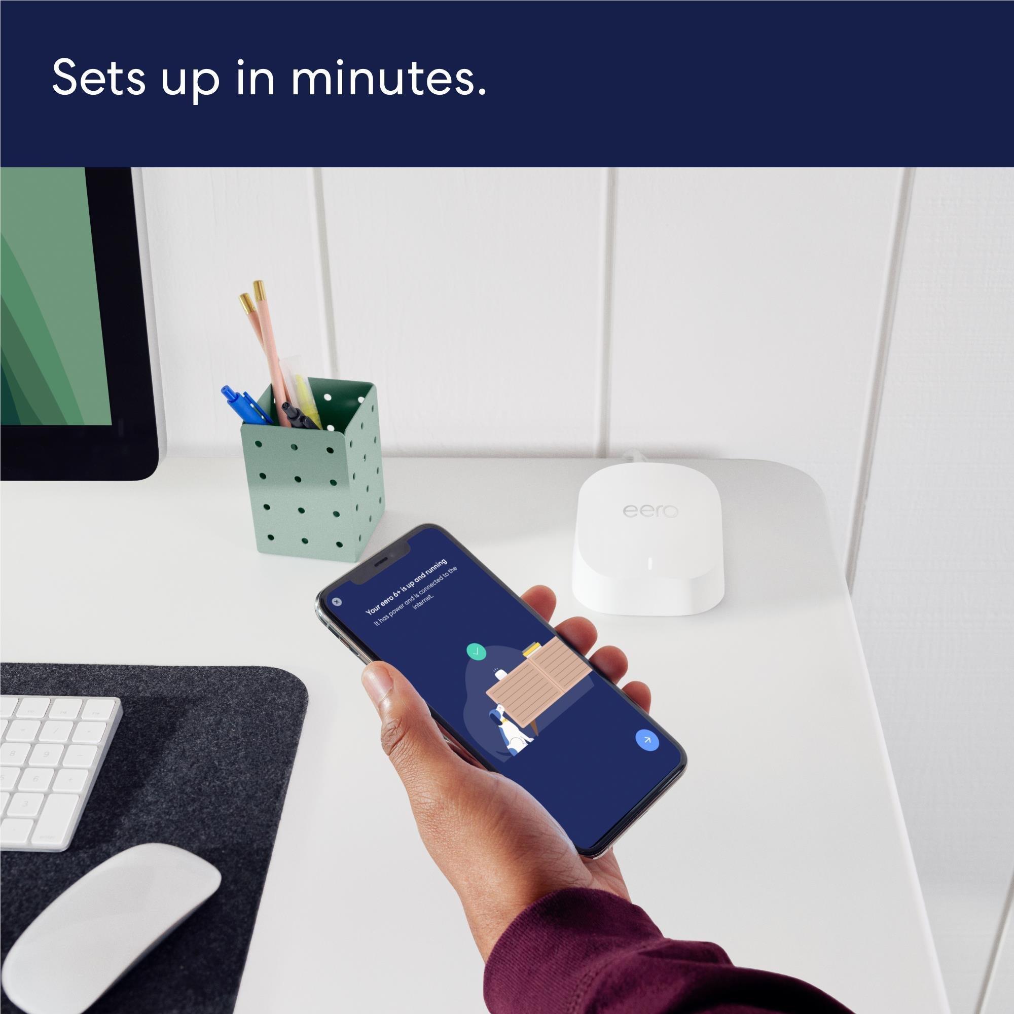 White eero mesh Wi-Fi router beside smartphone during app setup