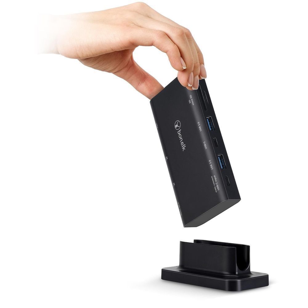 Black multiport USB-C hub held above its desktop stand