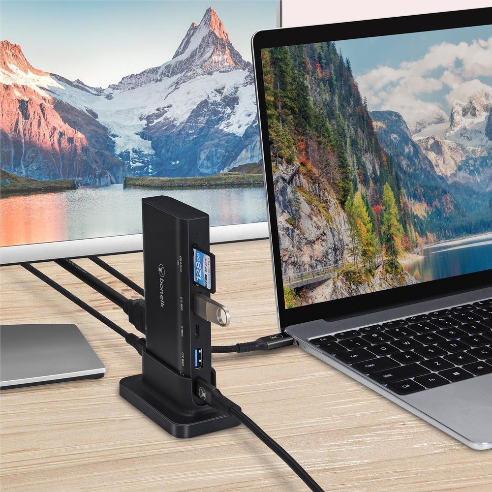 Black multiport desktop hub dock with side USB ports connected to laptops