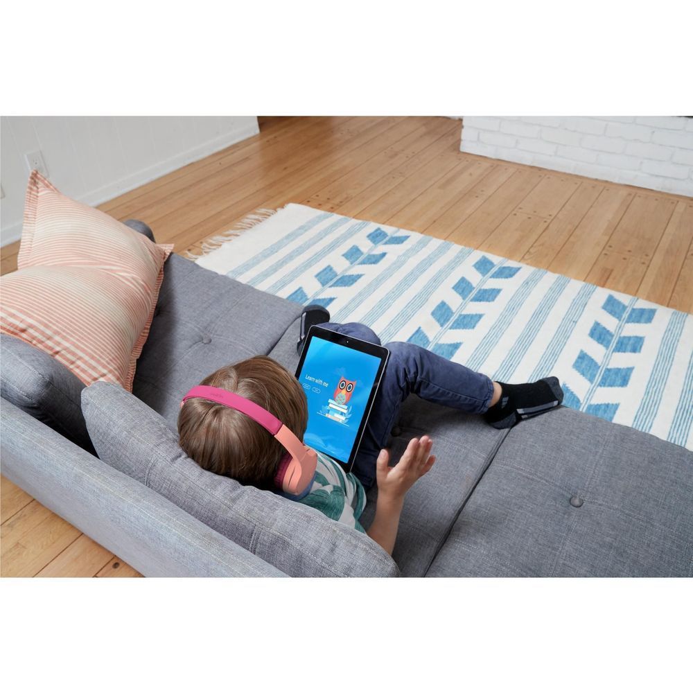 Pink kids wireless on-ear headphones on a child lying on couch, ear pads visible