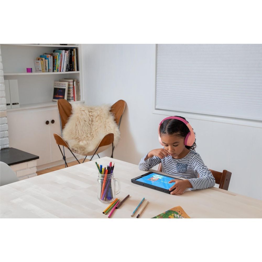 Pink kids wireless on-ear headphones on a child sitting at a table, padded cups