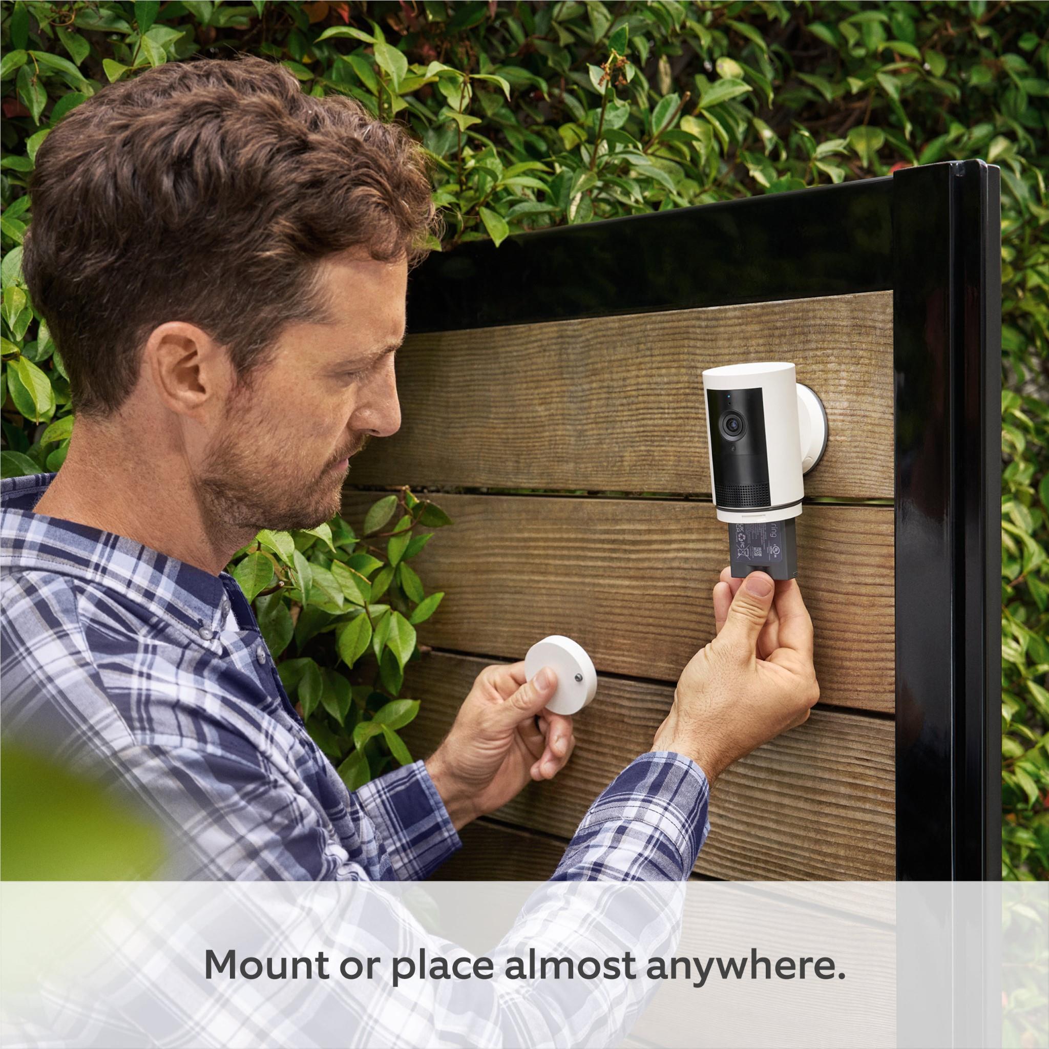 Outdoor battery security camera being mounted outdoors with tools and phone nearby