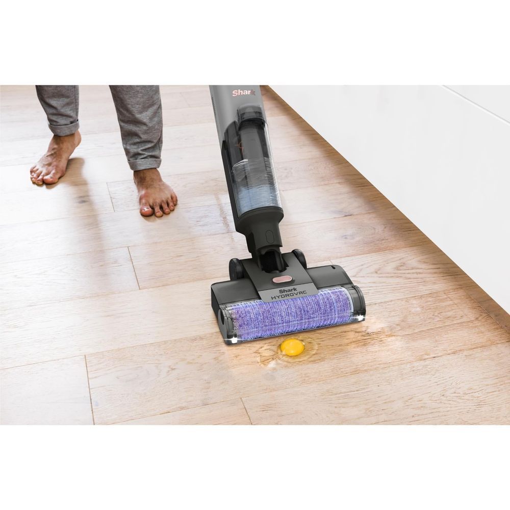 Cordless wet/dry vacuum with purple roller brush head cleaning a hardwood floor