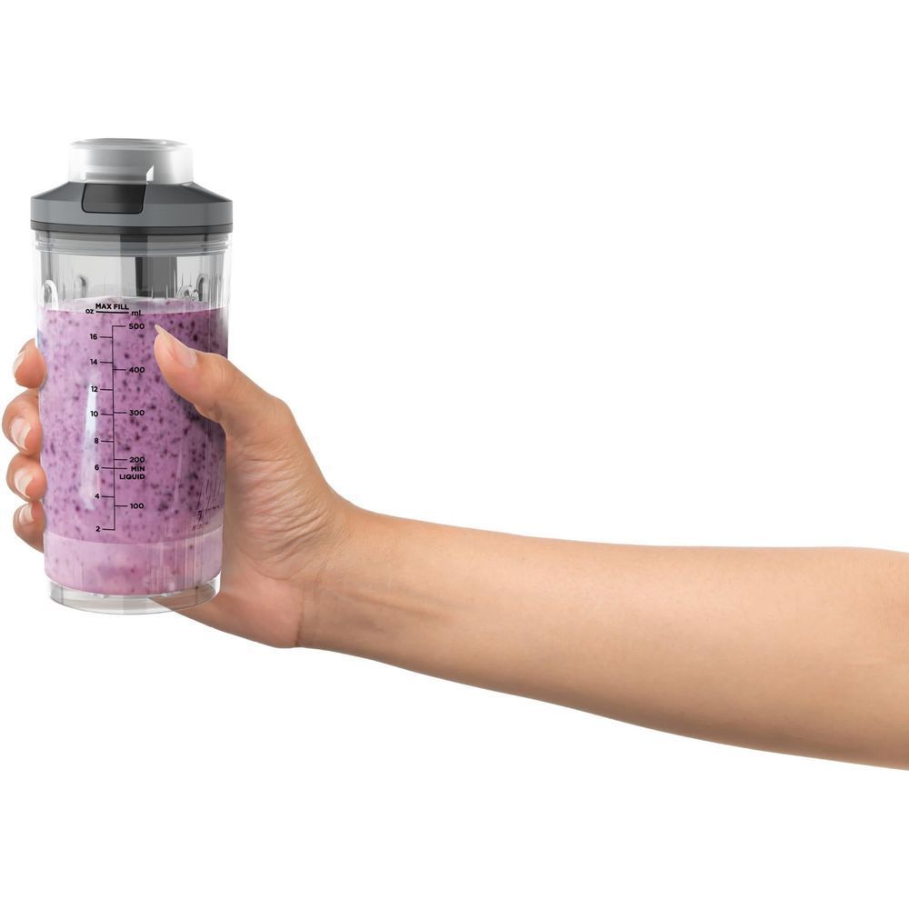 Hand holding cool grey Ninja cordless portable blender cup filled with purple smoothie