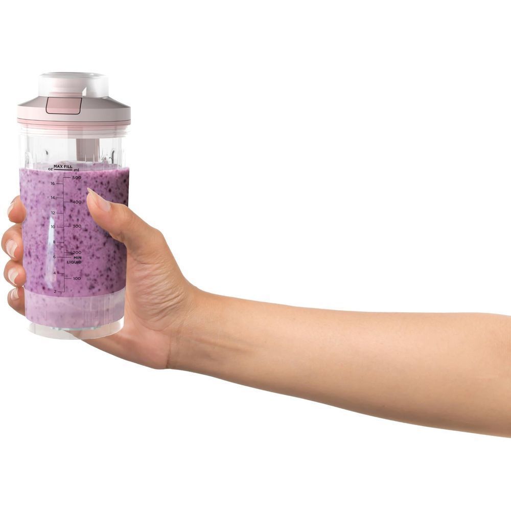 Dusty pink cordless portable blender held in hand with clear jar and purple smoothie