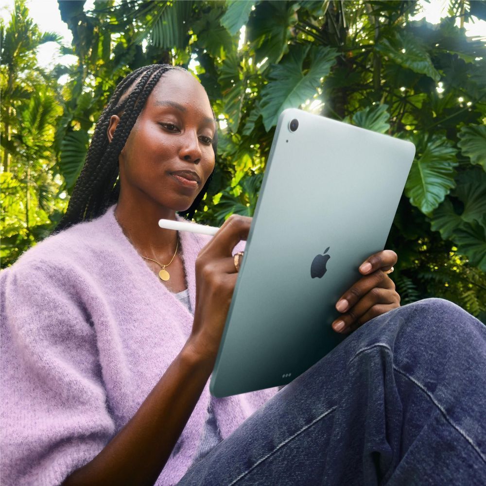 Blue iPad Air held in hand, showing the back and camera