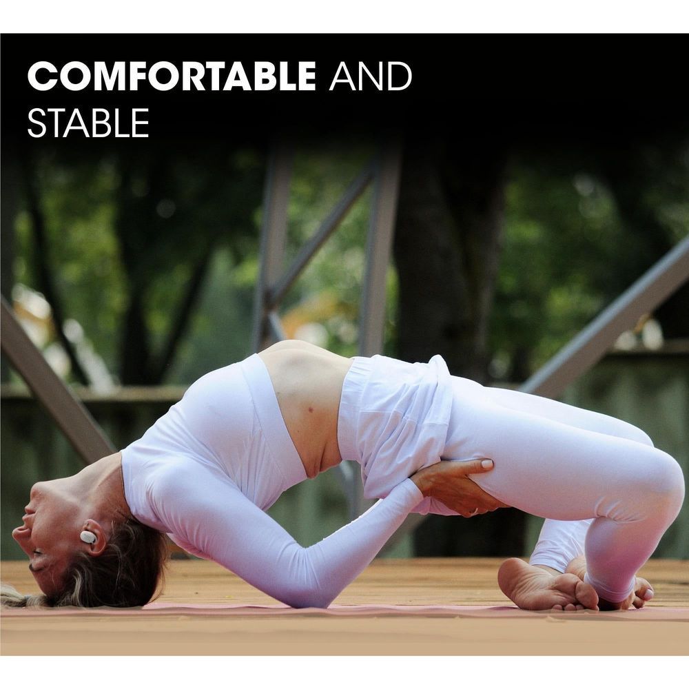 Woman doing yoga outdoors wearing white wireless earbuds in her ears