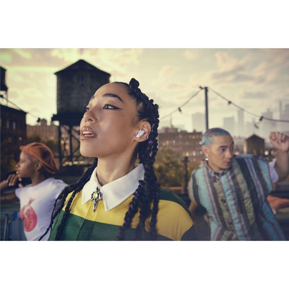 Person wearing white true wireless earbuds in a crowded outdoor setting