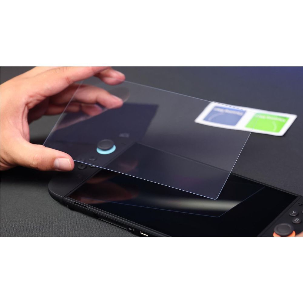 Hands applying tempered glass screen protector to handheld console display
