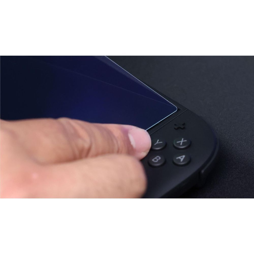 Close-up: hands aligning tempered glass screen protector over console controls