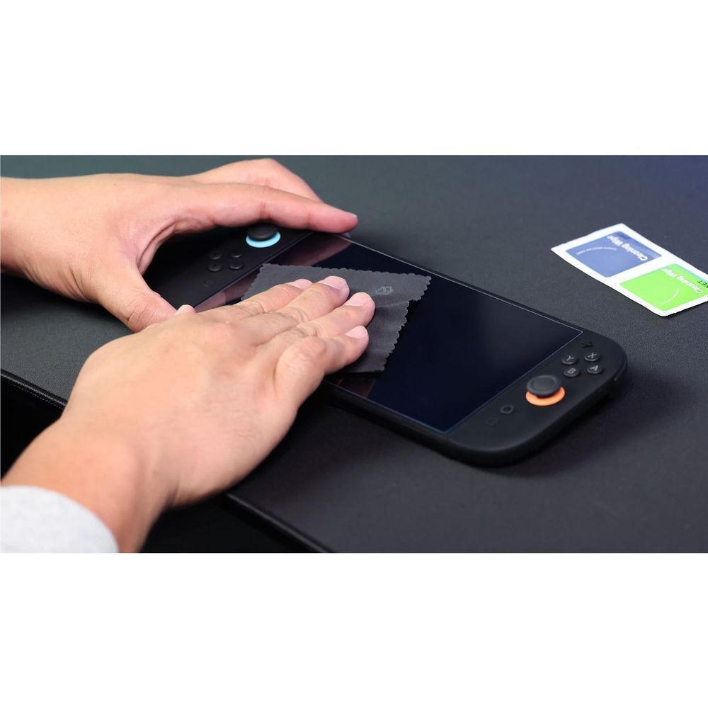Hands smoothing and cleaning tempered glass screen protector on handheld console