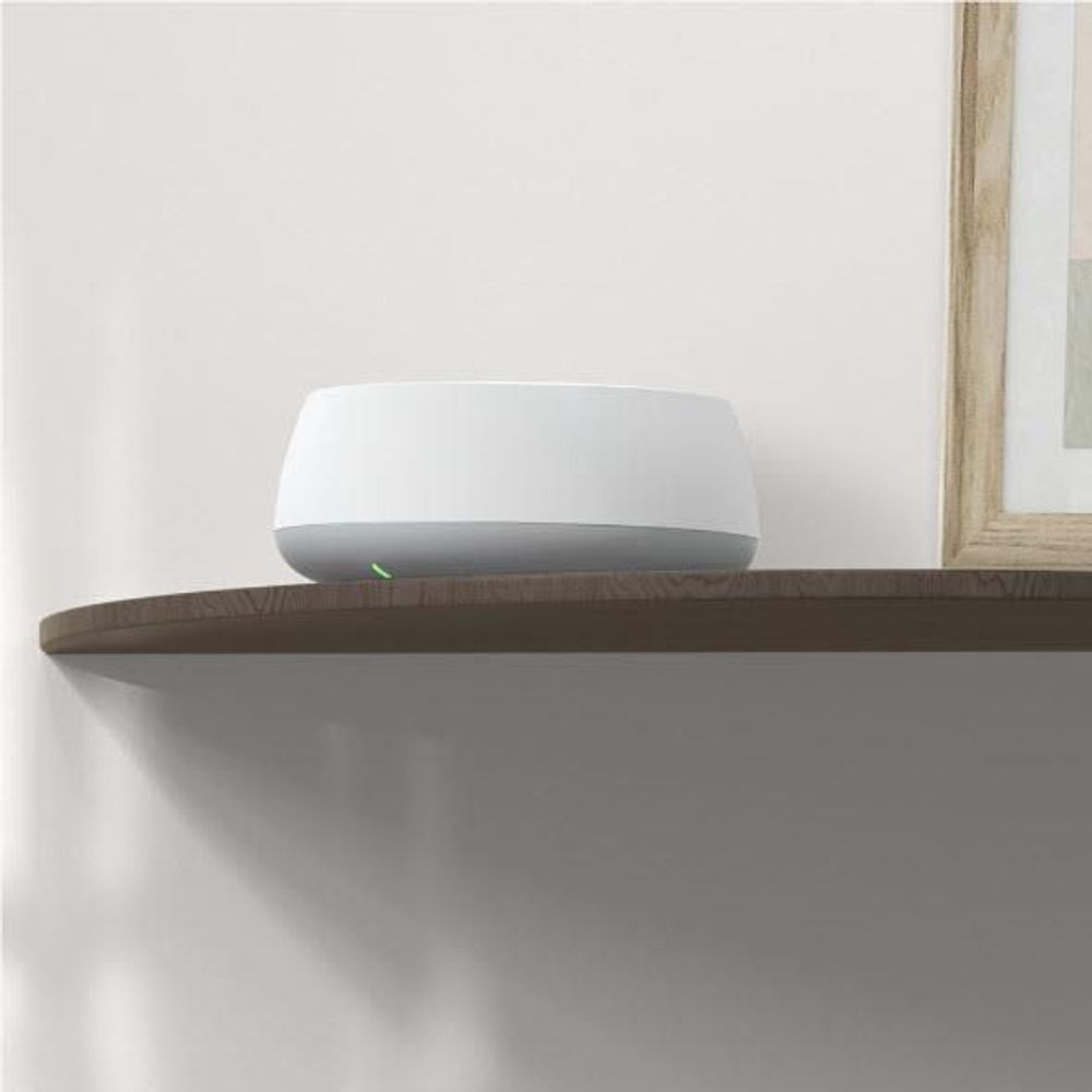 White TP-Link Deco mesh Wi-Fi 7 router on a wall shelf with green status LED