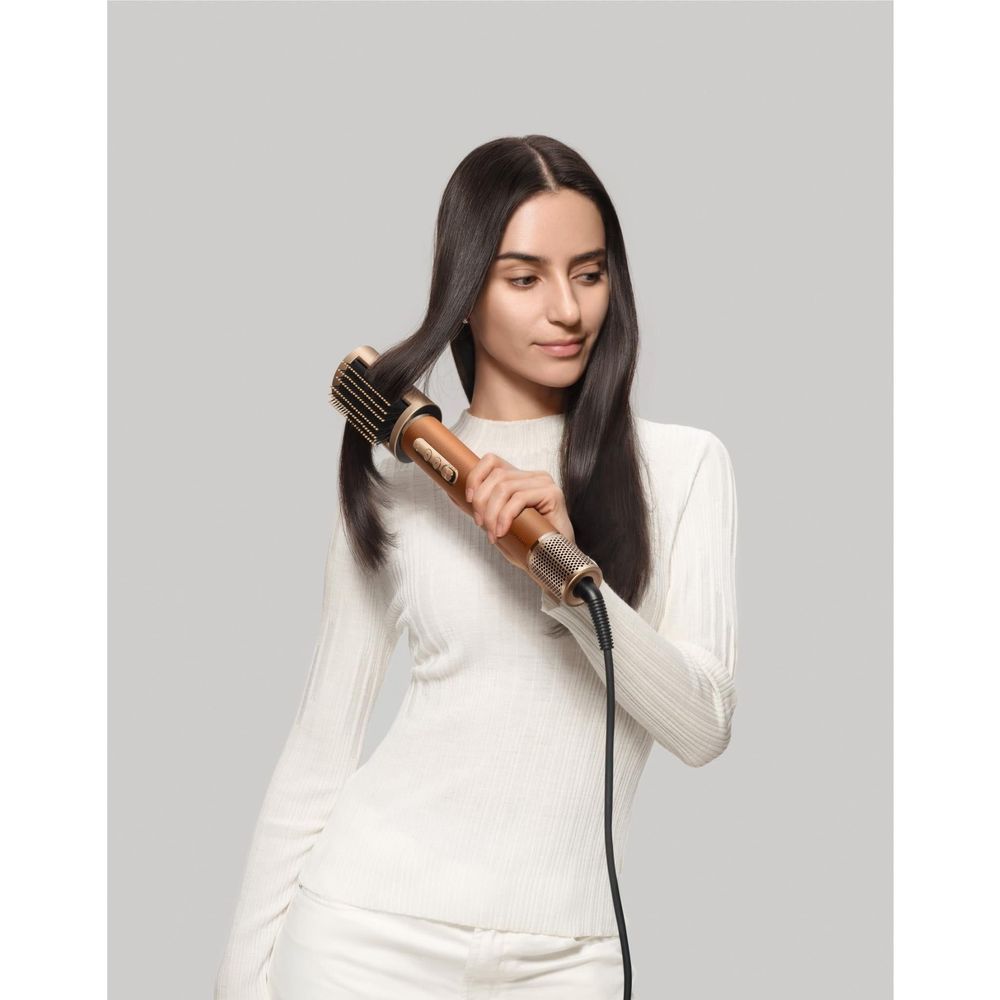Hair styling tool with gold barrel and comb attachment used on long hair