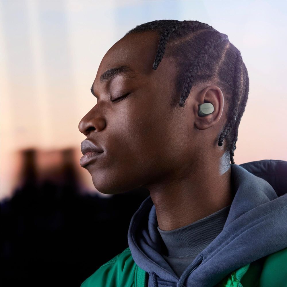 Forest green in-ear earbuds worn in ear on dark hoodie