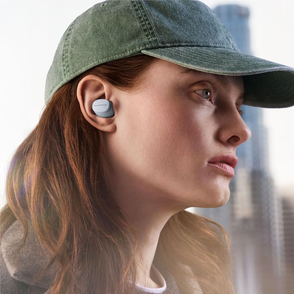 Glacier Blue wireless earbuds in ear on a person wearing a cap