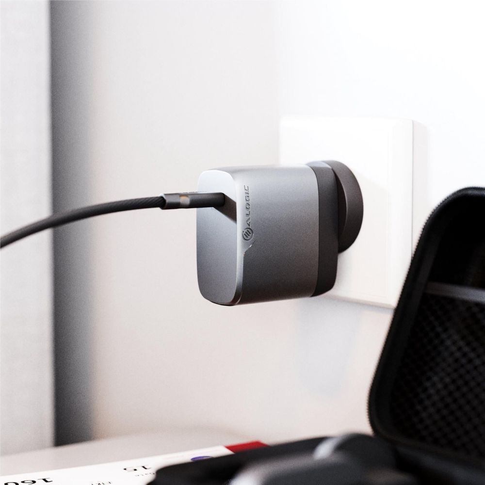 Space grey travel charger plugged into a wall outlet with USB-C cable connected