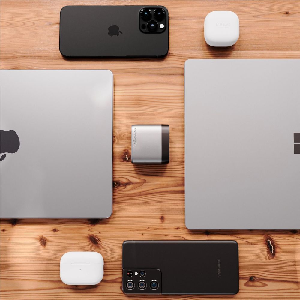 Space grey 67W PD travel charger placed between laptops and smartphones with cables