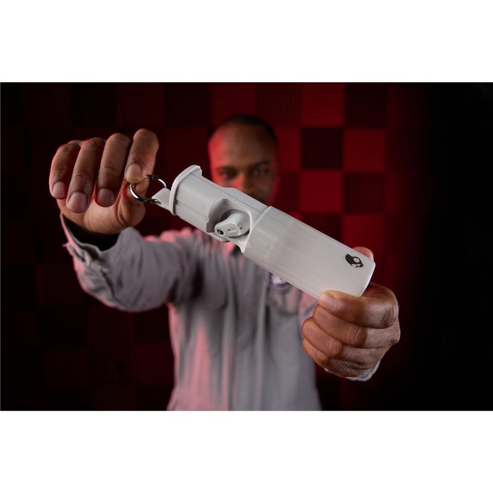 White keychain charging case with earbuds, held by a person