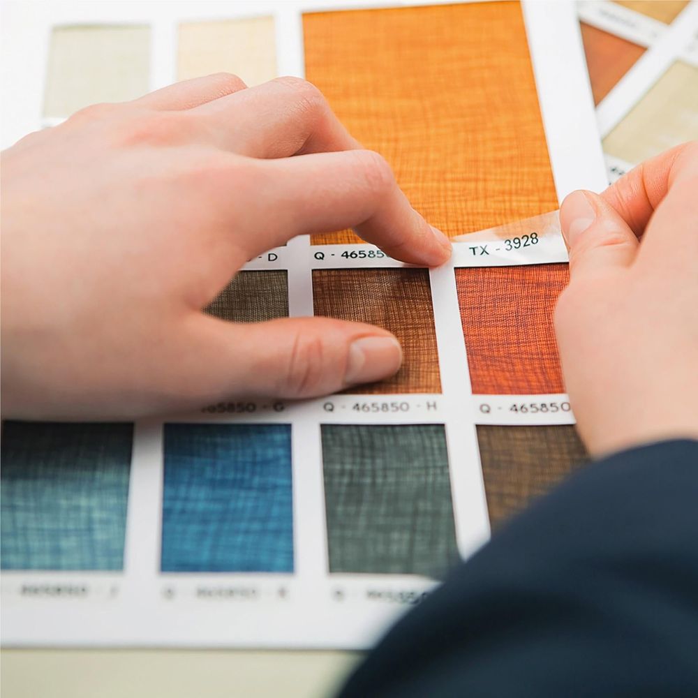 Hands placing label strips onto swatch cards for organizing colors and samples