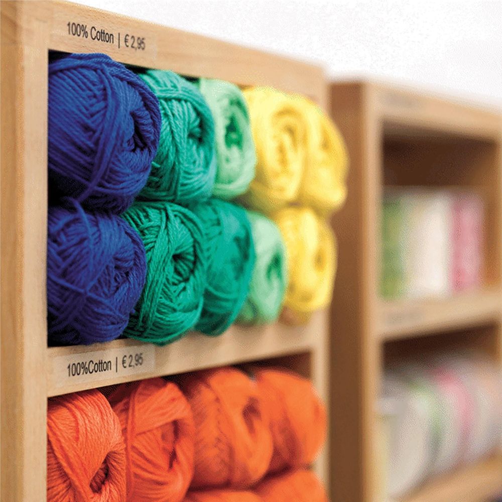 Colored yarn balls with small printed price label tags on wooden shelf