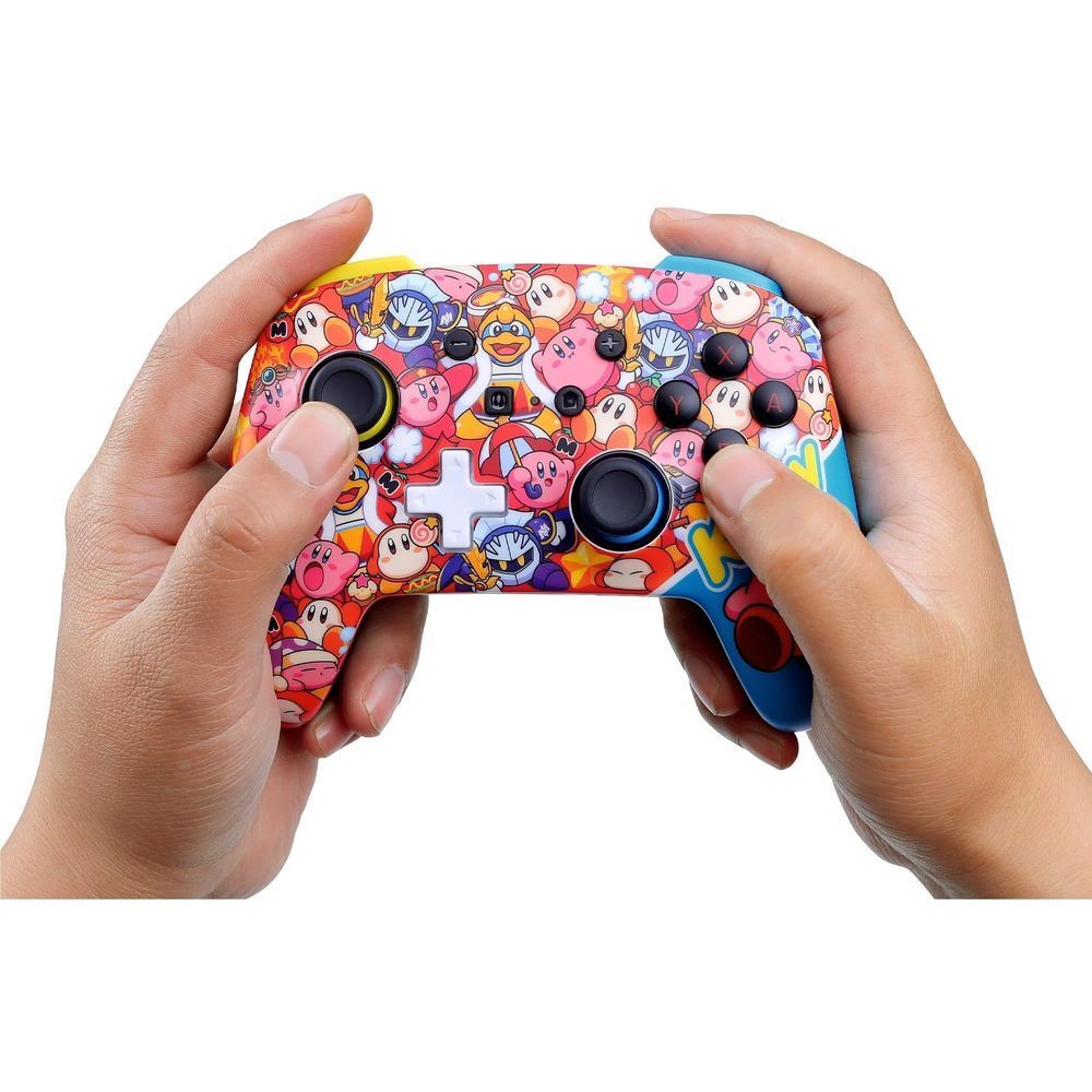 Hands holding Kirby-themed wireless controller with black thumbsticks and colorful buttons