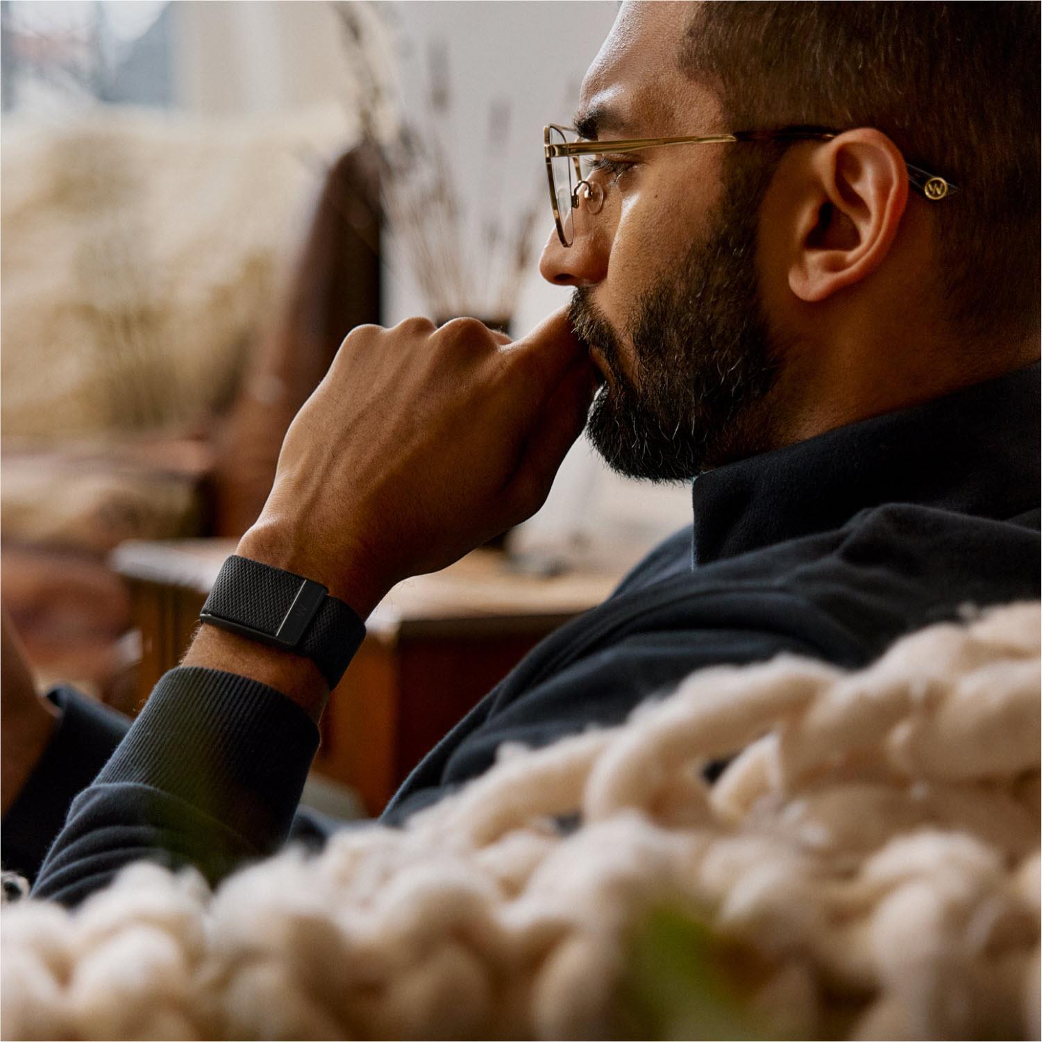 Man wearing a black fitness tracker on his wrist indoors