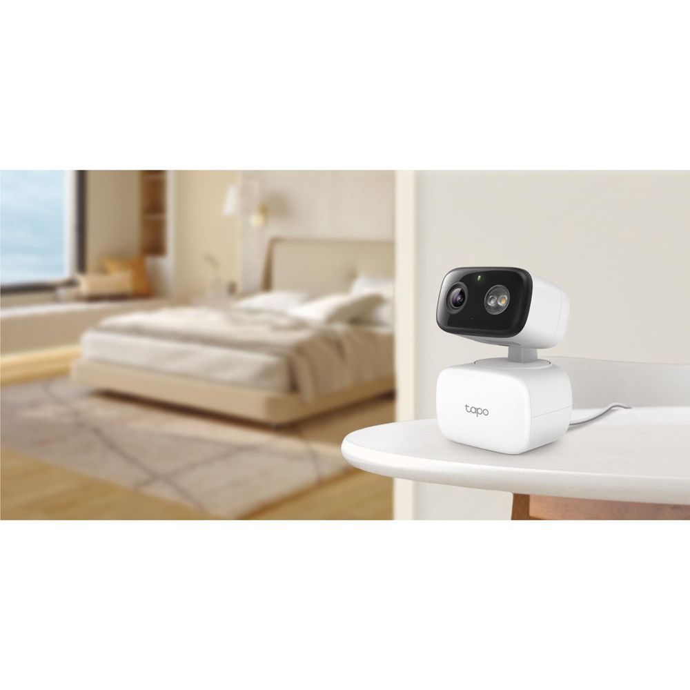 Indoor/outdoor pan-tilt security camera on table with white base and black lens module